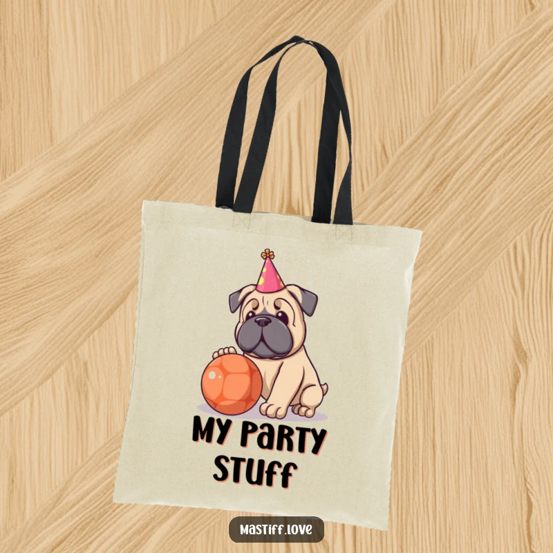 Funny tote bag featuring a kawaii Mastiff wearing a tiny party hat, happily playing with a very large ball.